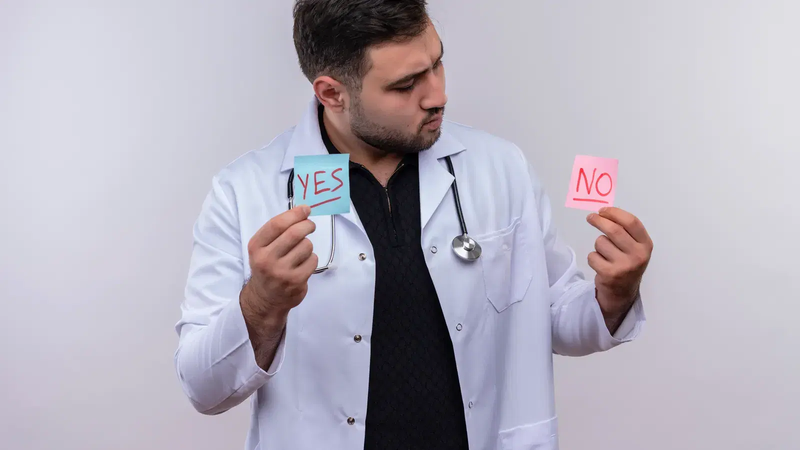 A clinician in a white coat weighing up a yes note in one hand and a no note in the other